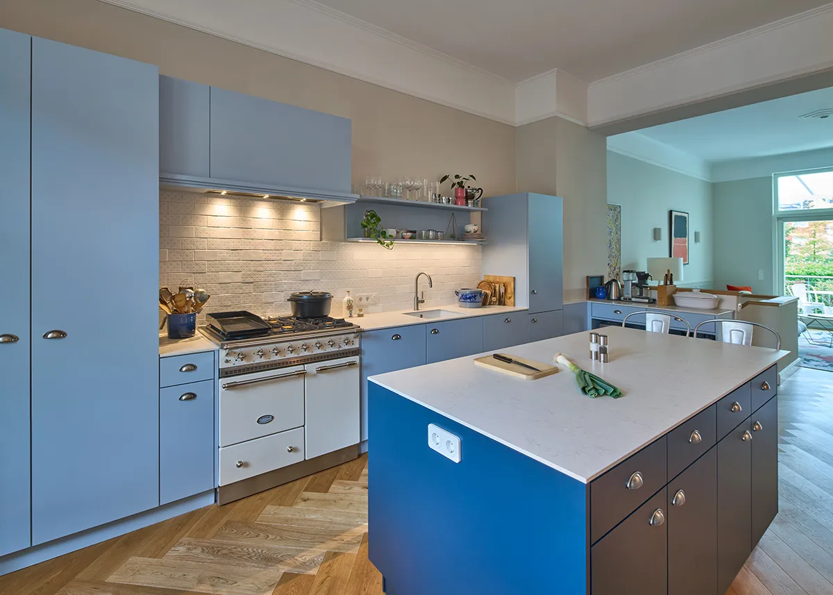 Essbereich in der modernisierten Maisonettewohnung mit Erkerfenstern, heller Kochinsel und maßgefertigter Küchenzeile in hellblau.